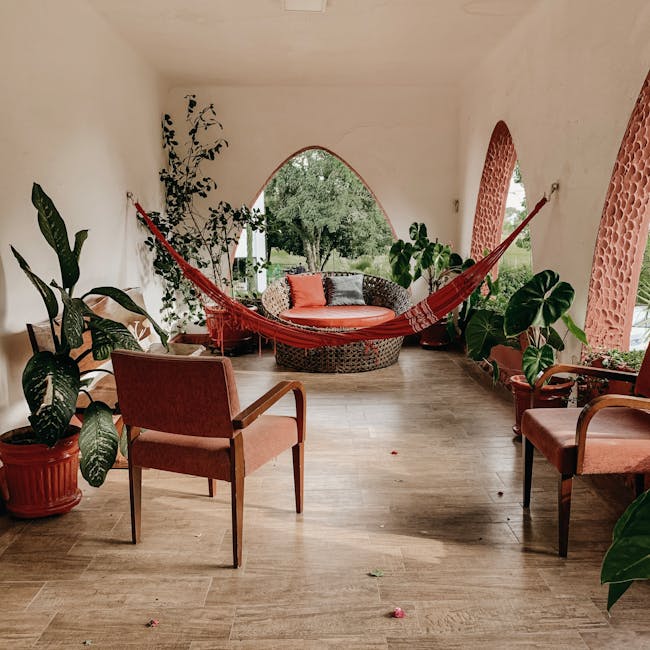 Serene indoor patio featuring a hammock, lush green plants, and comfortable seating for relaxation.